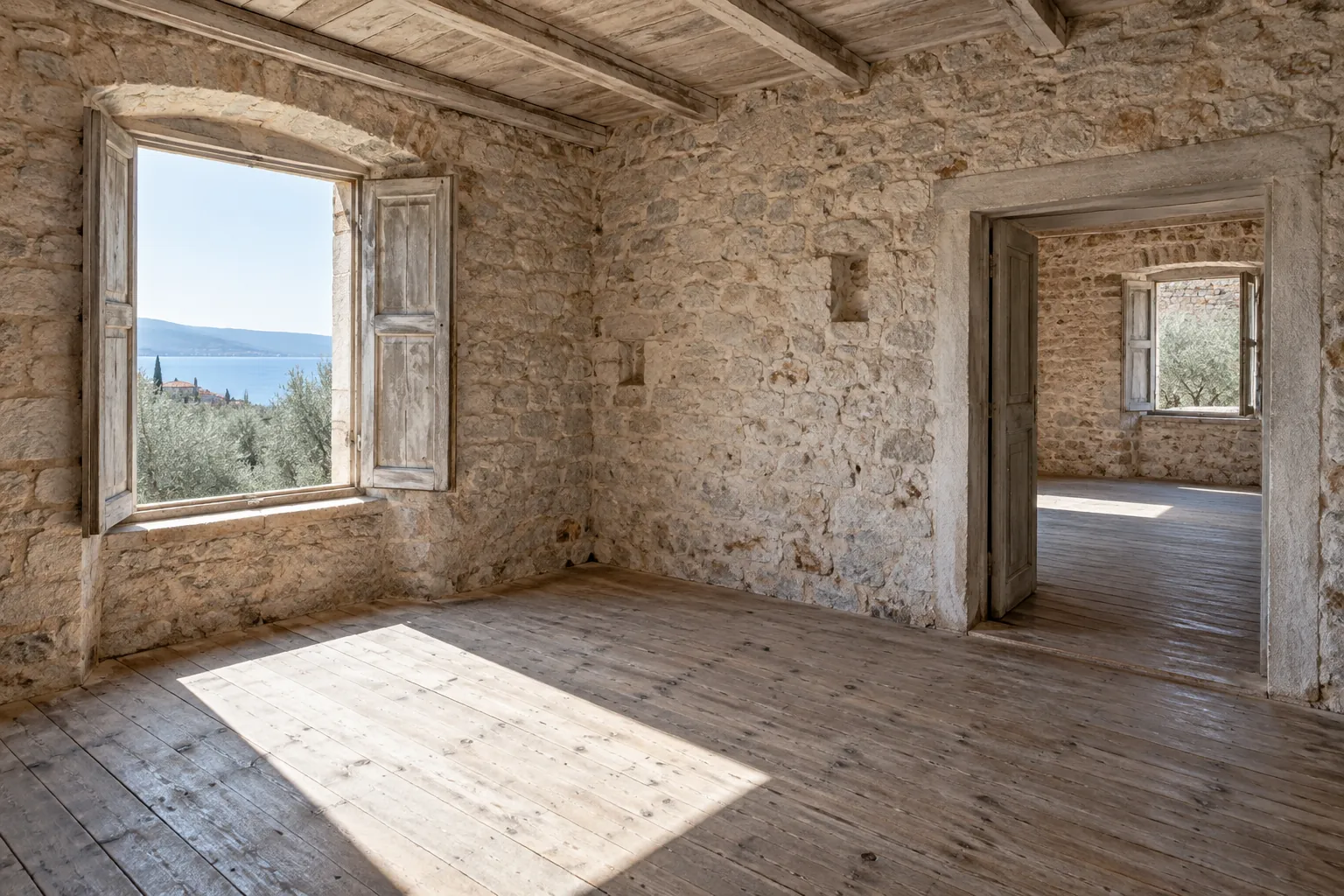 Leerer, heller Raum eines alten Steinhauses mit offenem Fensterladen und Blick aufs Meer