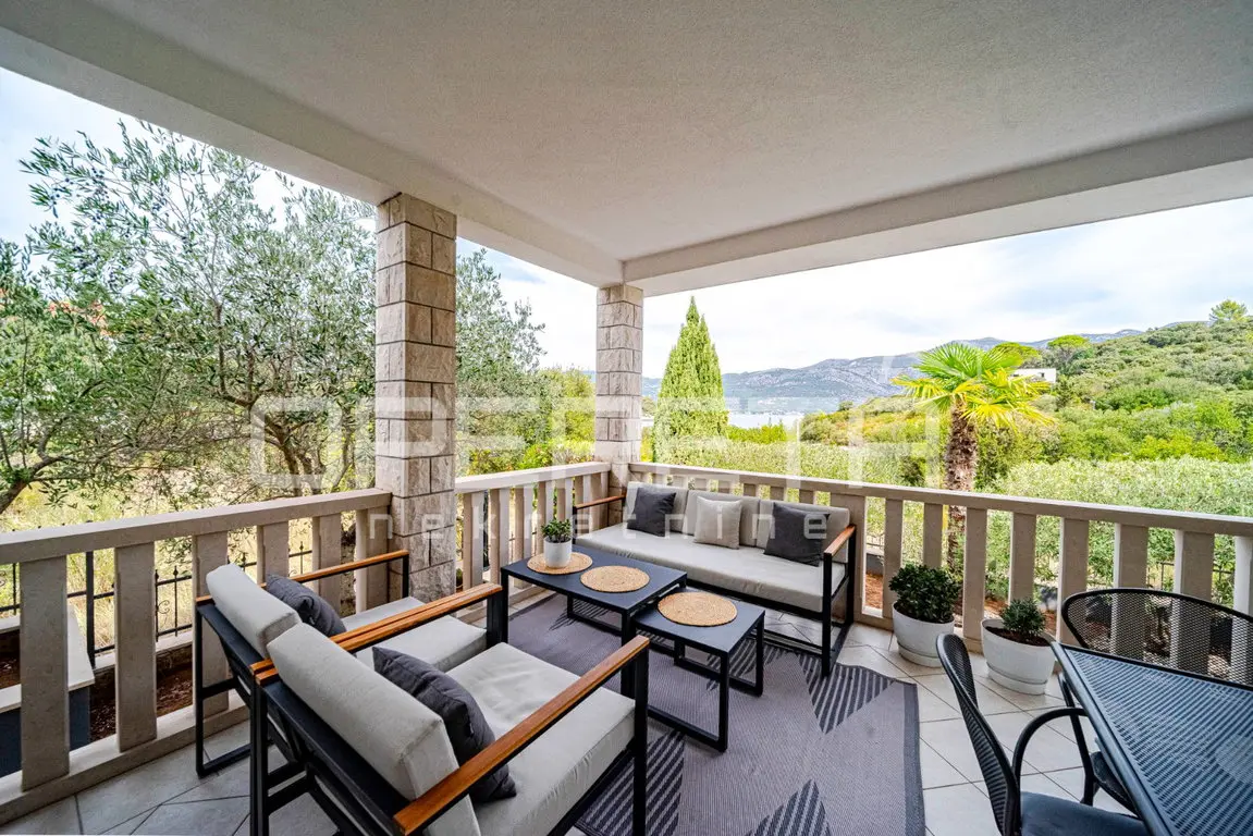 Terrasse mit Lounge-Möbeln und Blick über den Garten aufs Meer