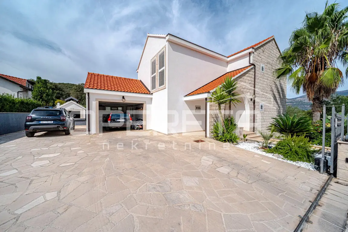 Zufahrt und Garage des Hauses mit Palmen