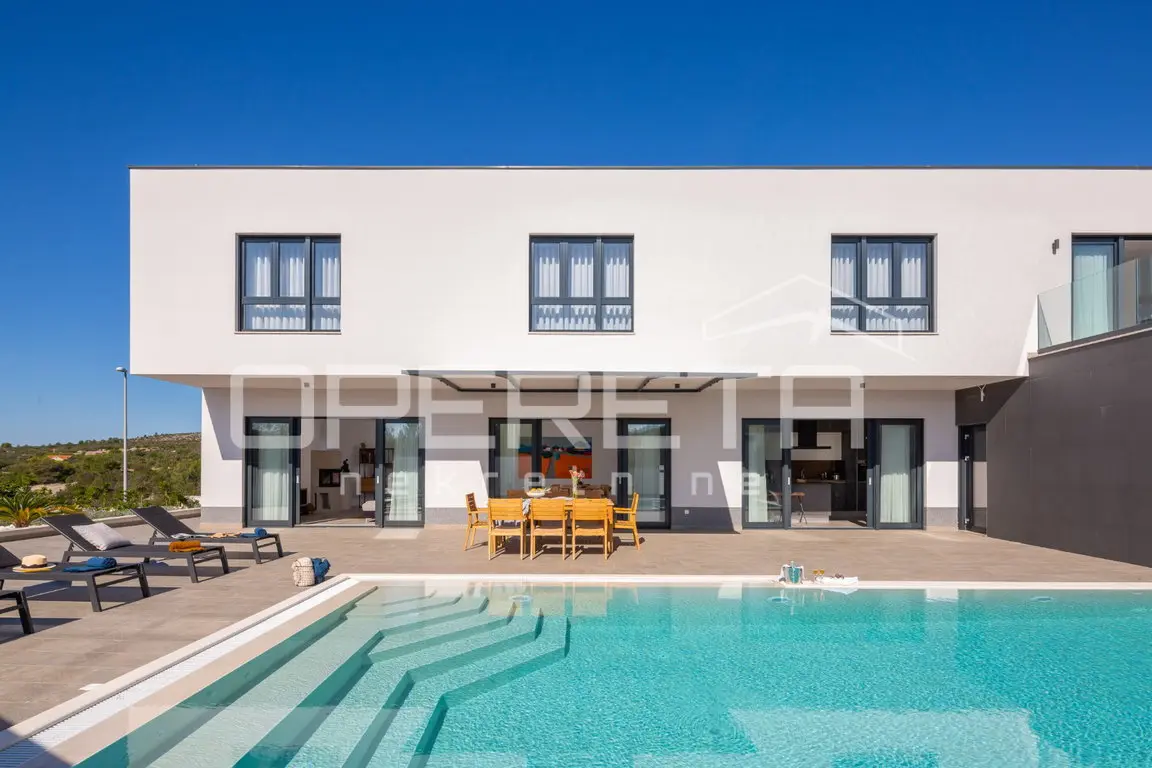 Pool mit Treppe vor der weißen Fassade der modernen Villa und Essplatz auf der Terrasse