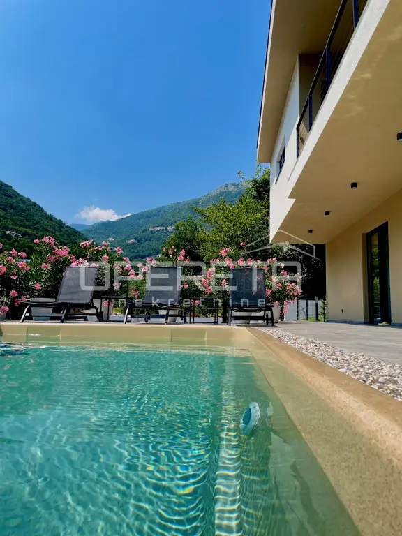 Pool mit Liegen und blühendem Oleander vor bewaldeten Berghängen