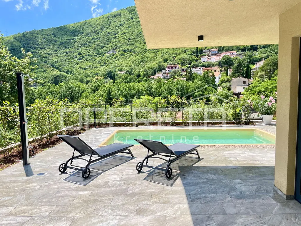 Pool-Terrasse mit zwei Liegen und Blick auf grüne Hänge
