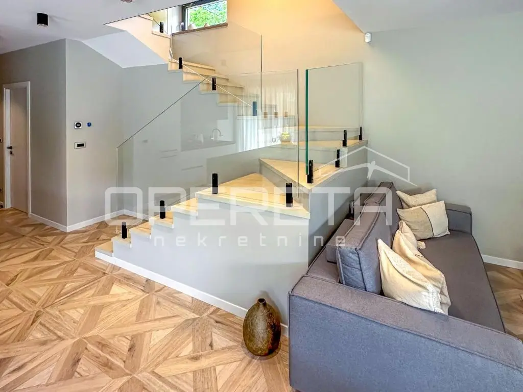 Wohnbereich mit Sofa und Glastreppe ins Obergeschoss