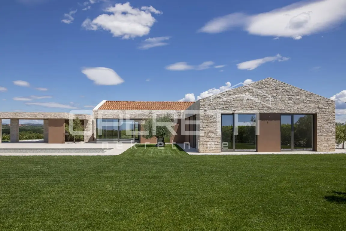 Längsfassade der Villa mit Natursteingiebel, Glasfronten und Rasen