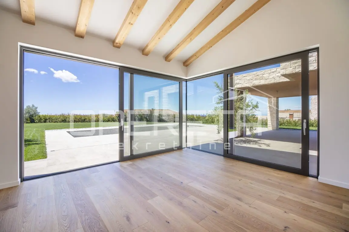 Wohnraum mit Holzbalkendecke, Holzboden und raumhoher Eckverglasung zur Pool-Terrasse