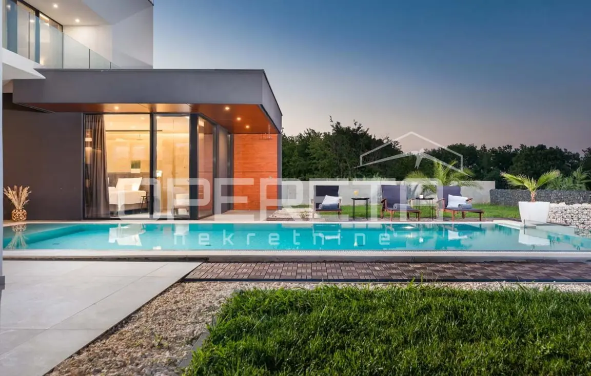 Pool vor der beleuchteten Glasfassade der Villa am Abend