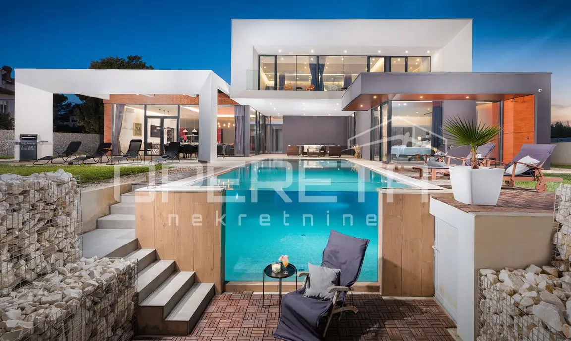 Pool mit Glaswand, Holzdeck und Steintreppe vor der Villa