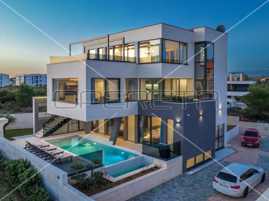 Moderne mehrgeschossige Villa mit beleuchtetem Pool in der Abenddämmerung