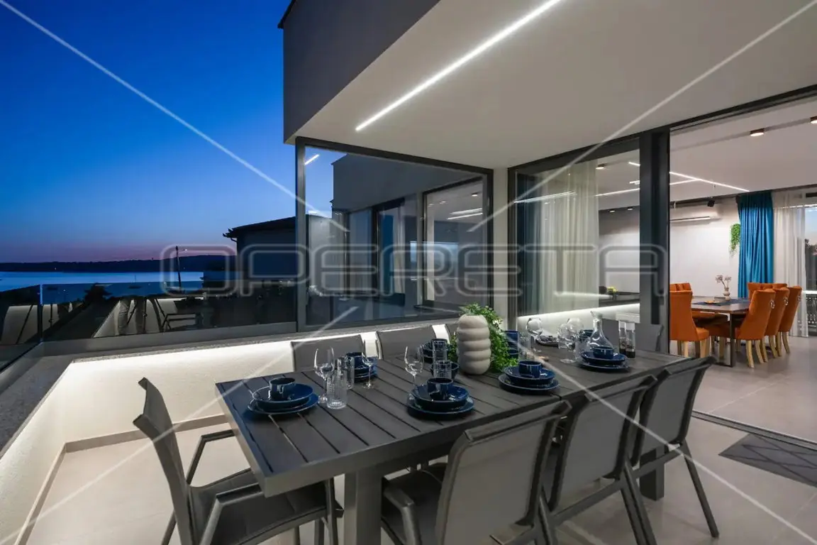 Gedeckter Tisch auf der Terrasse bei Dämmerung mit Blick aufs Meer