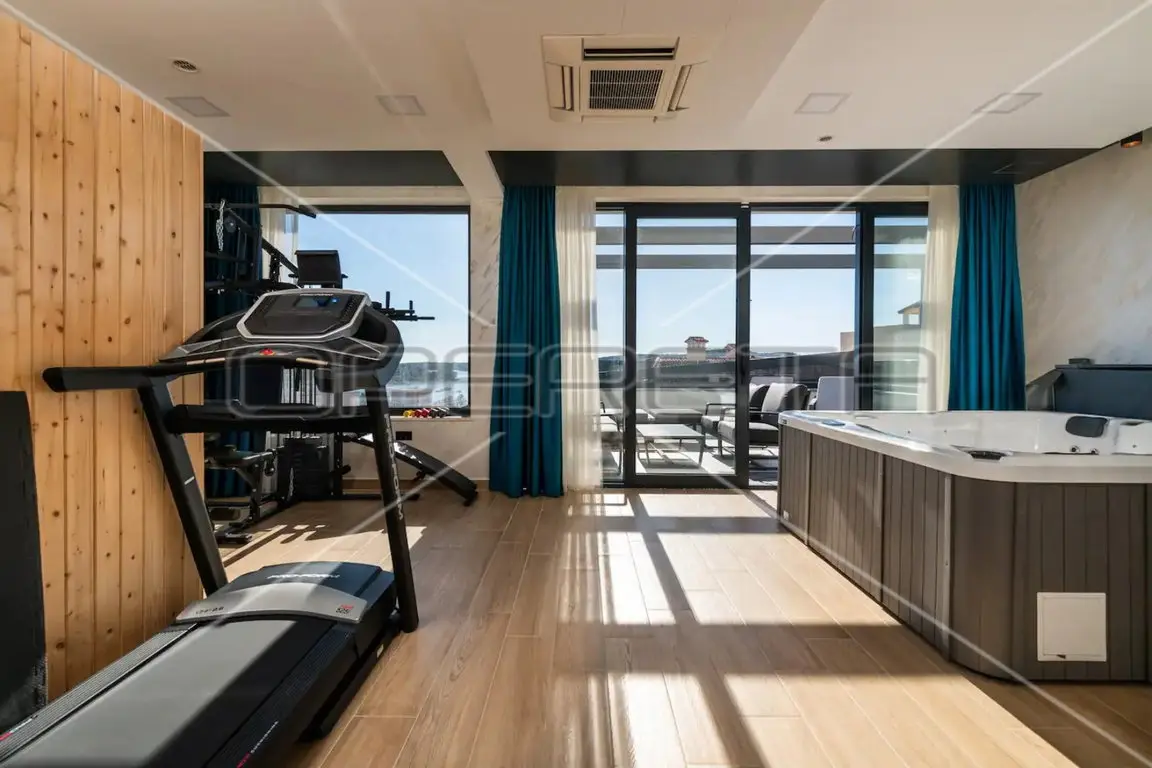 Wellness- und Fitnessbereich mit Whirlpool, Laufband und Fensterfront